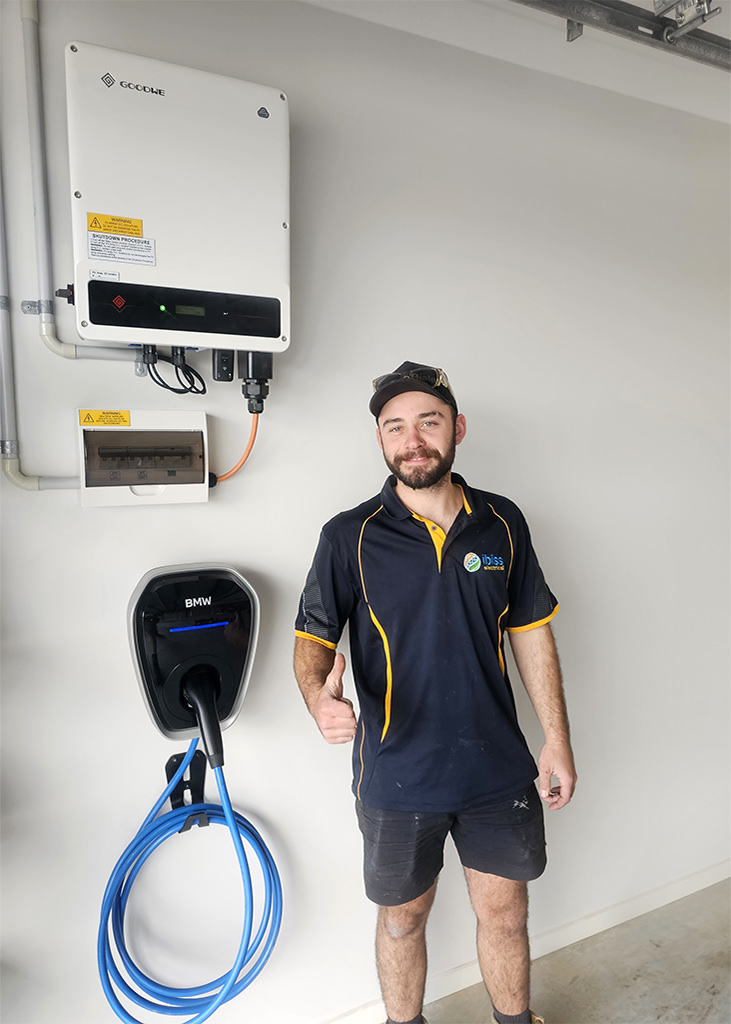 A happy electrician that has installed an EV wall charger for his client. He is smiling and giving a thumbs up.