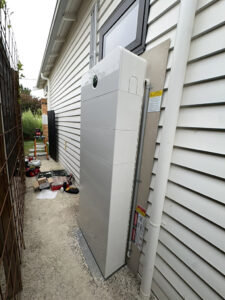 Side view of a Sigenergy SigenStor battery system installed in a narrow outdoor walkway.