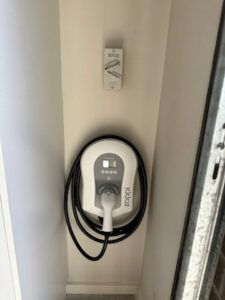 A Myenergi Zappi solar-aware EV charger mounted on an interior wall with cable management.