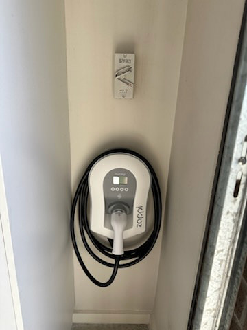 A Myenergi Zappi solar-aware EV charger mounted on an interior wall with cable management.