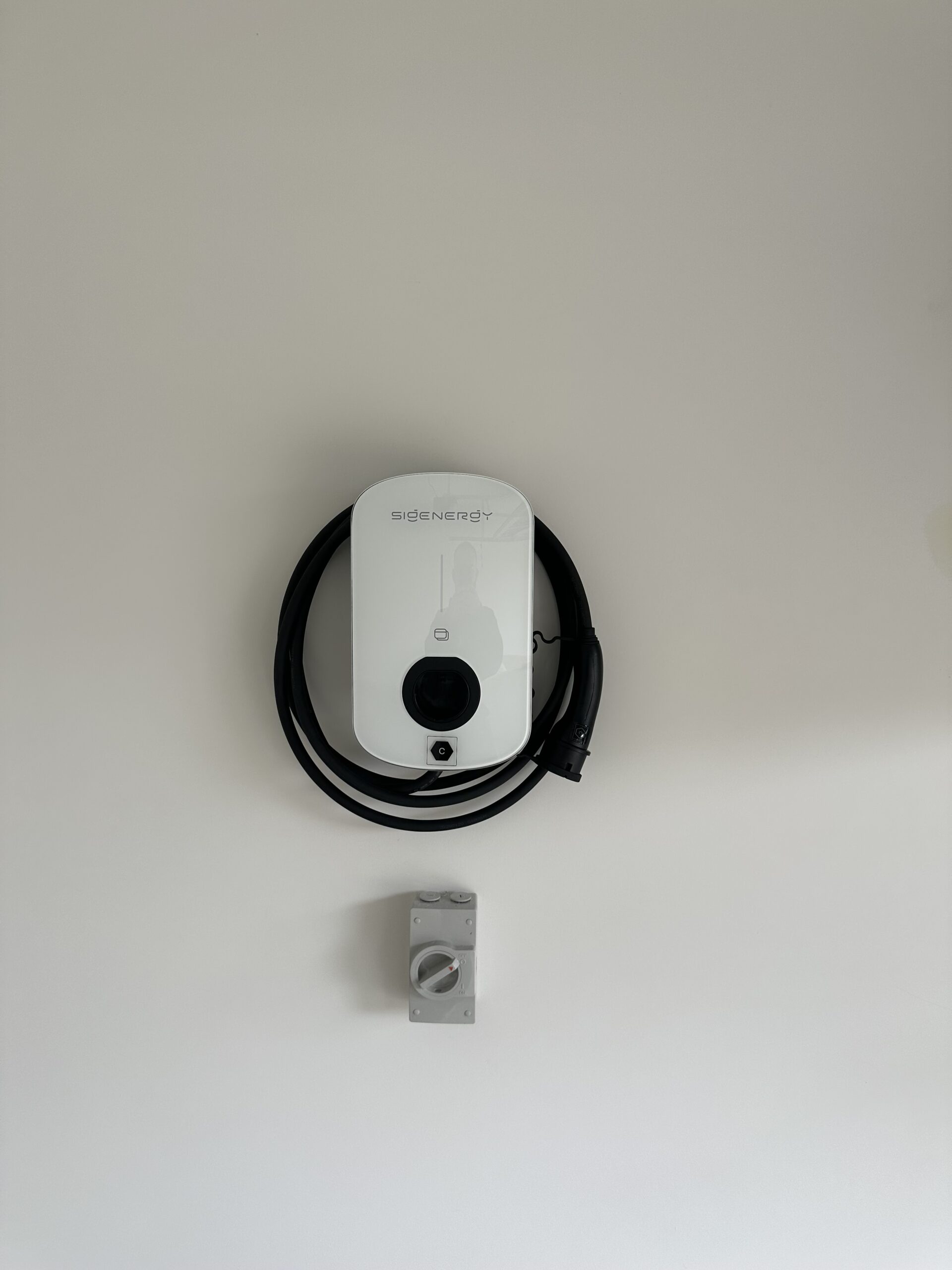 A BMW wall charger for an EV vehicle installed on the wall inside a domestic garage.